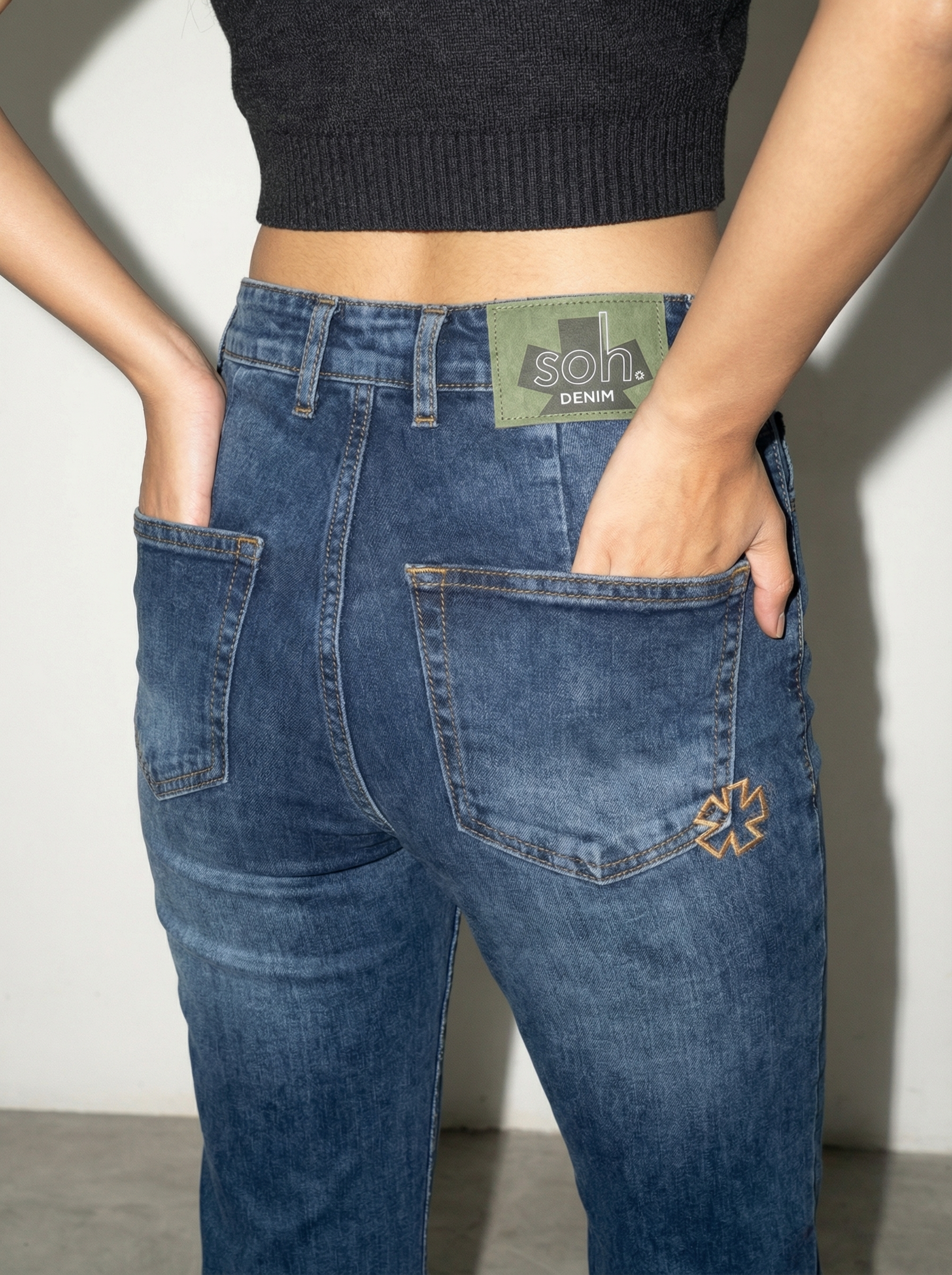 Person wearing blue jeans with a visible brand label against a neutral background