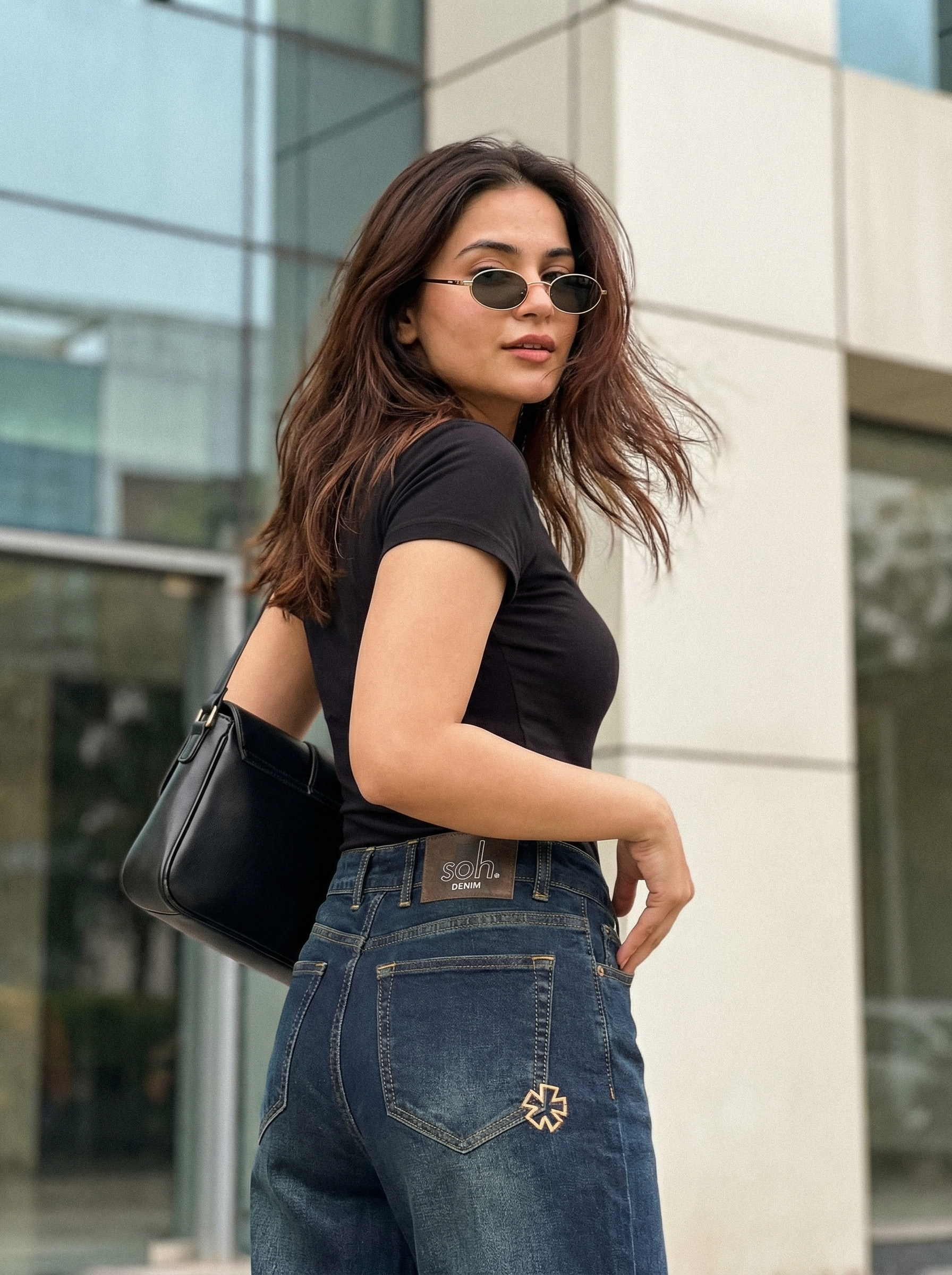 Woman wearing sunglasses, black top, and Nova Afterlight Indigo jeans