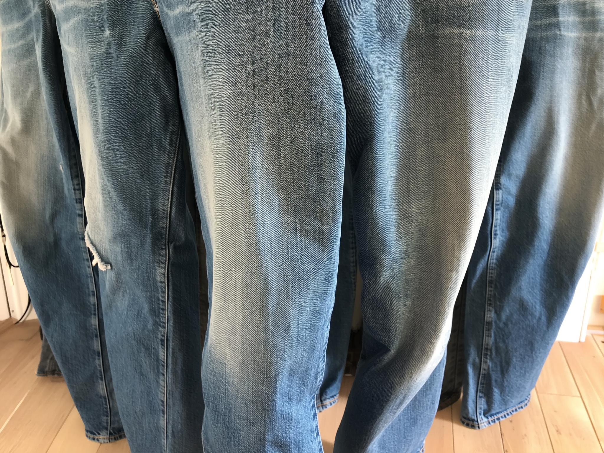 Stack of blue SOH jeans on a wooden floor