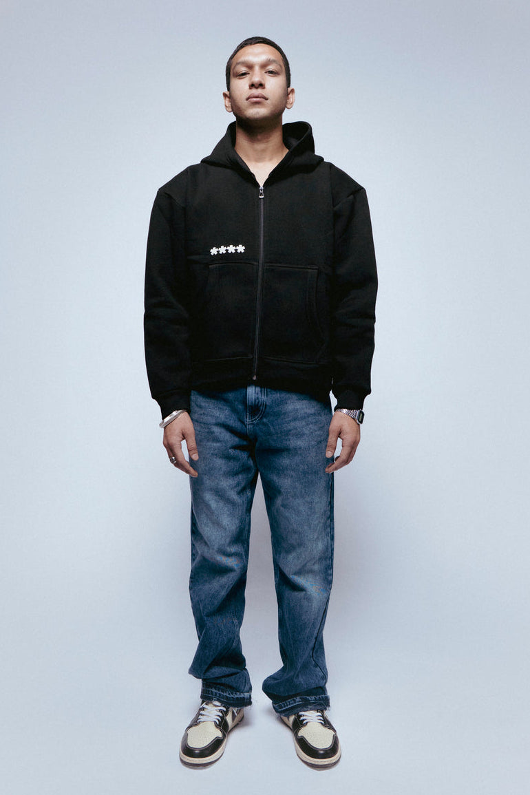 Man wearing a SOH Hoodie Error 01 with a zipper and blue jeans on a light gray background