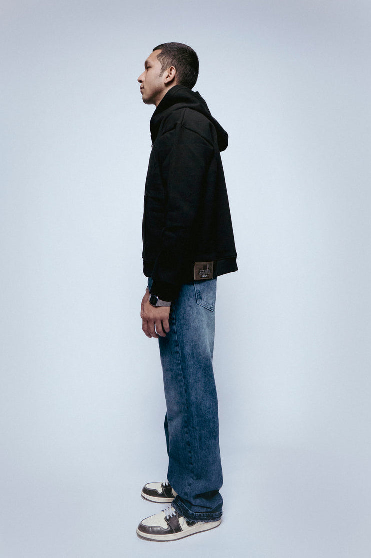 Person wearing a SOH Hoodie Error 01 and blue jeans standing against a white background