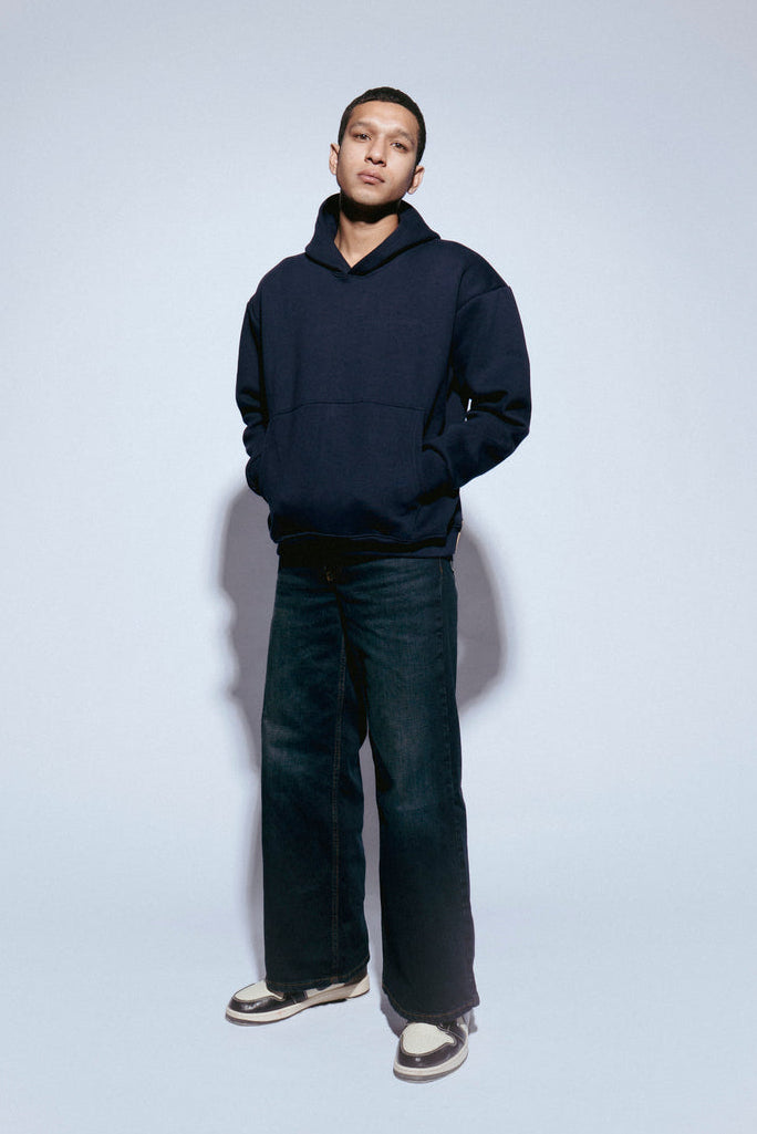 Person wearing a SOH Hoodie Error 02 and jeans on a light gray background