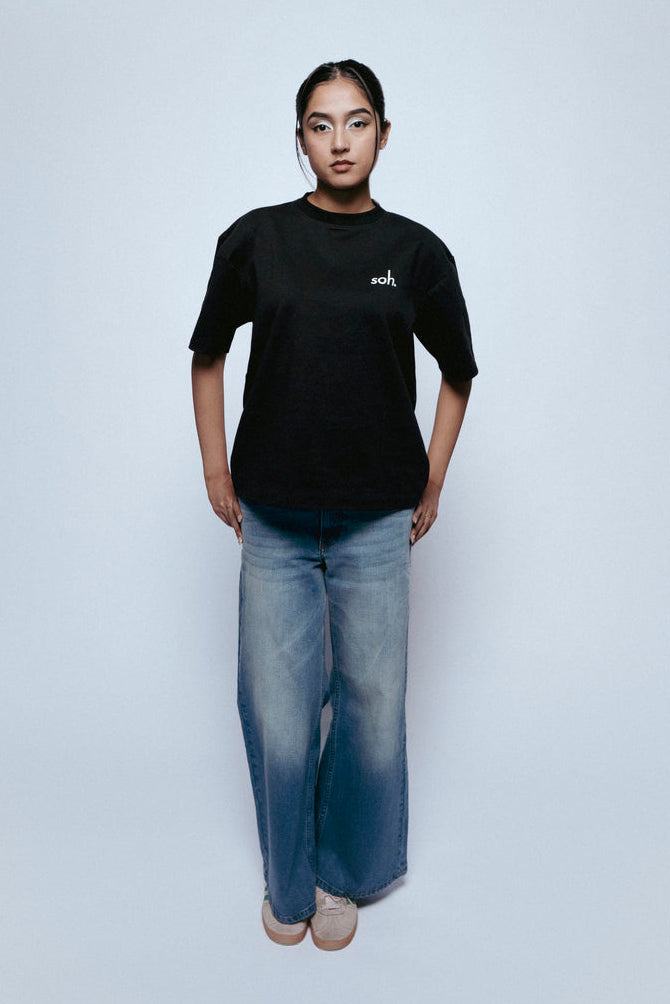 Person wearing a black SOH Mark T-shirt and SOH Morning Indigo jeans on a white background