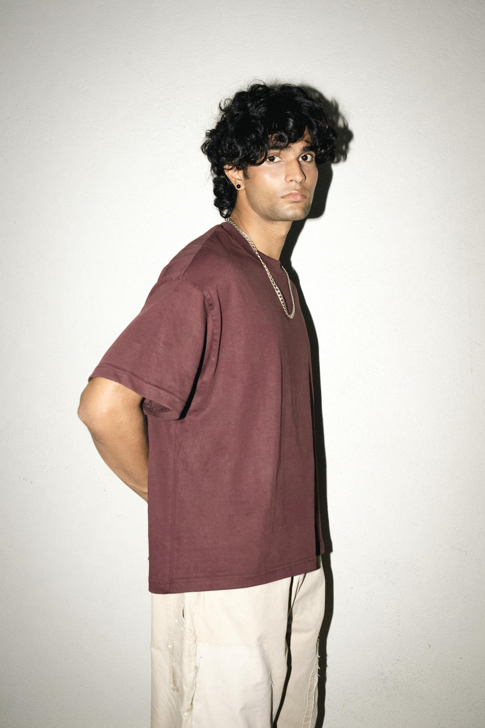 Person wearing a maroon SO t-shirt and light-colored pants against a plain background