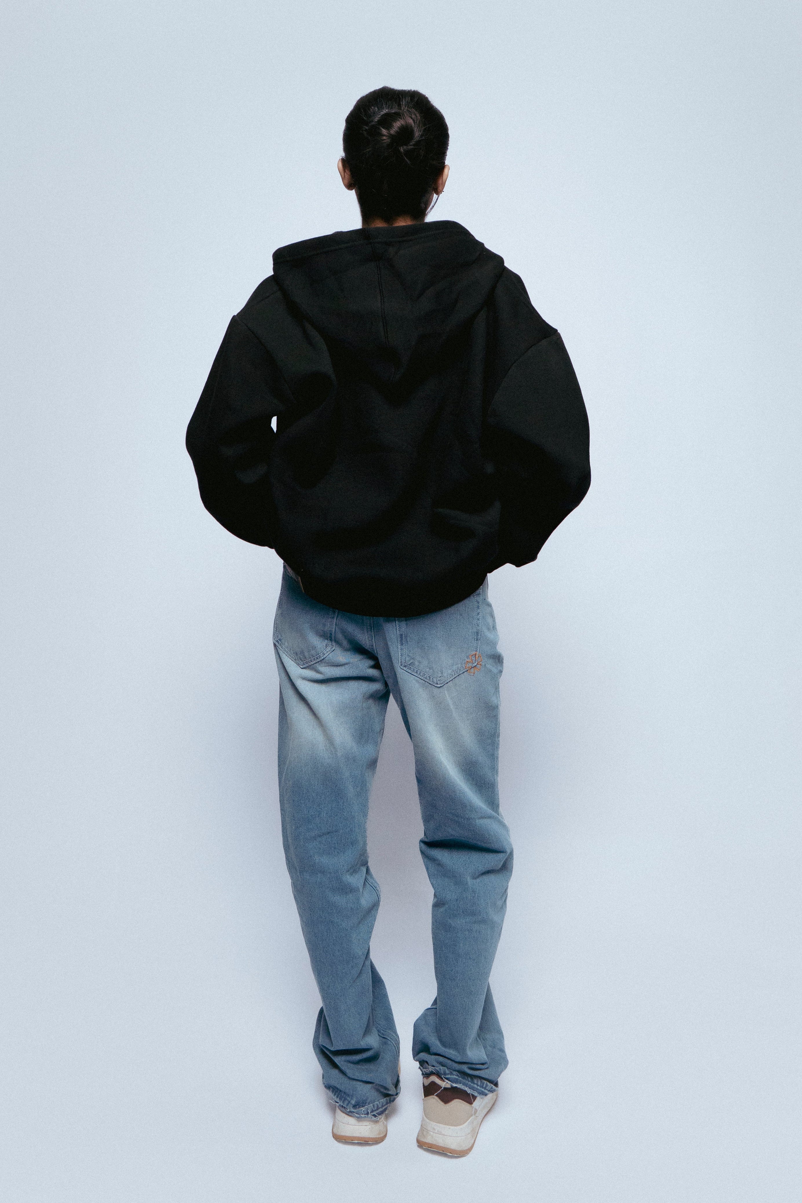Person wearing a SOH Hoodie Error 01 and SOH NOIR jeans on a white background
