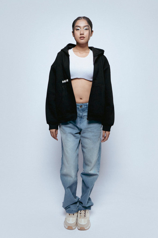 Person wearing a SOH Hoodie Error 01, white crop top, SOH Noir jeans, and white sneakers on a light gray background