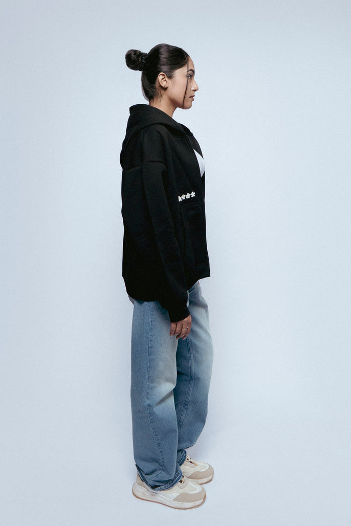 Woman wearing a SOH Hoodie Error 01 and SOH Noir jeans standing against a white background