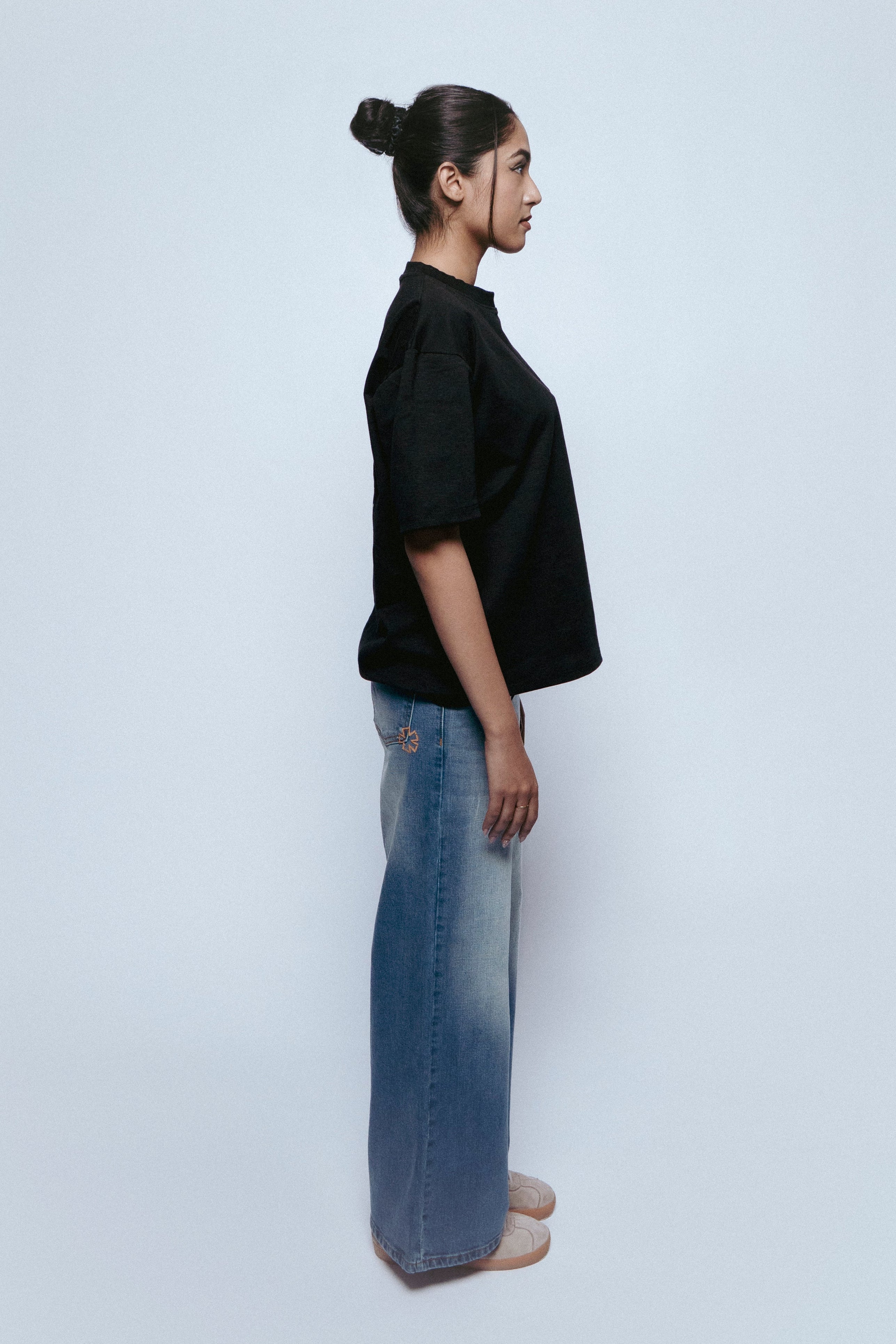 Person wearing a black SOH Mark t-shirt and SOH Nova jeans standing against a white background