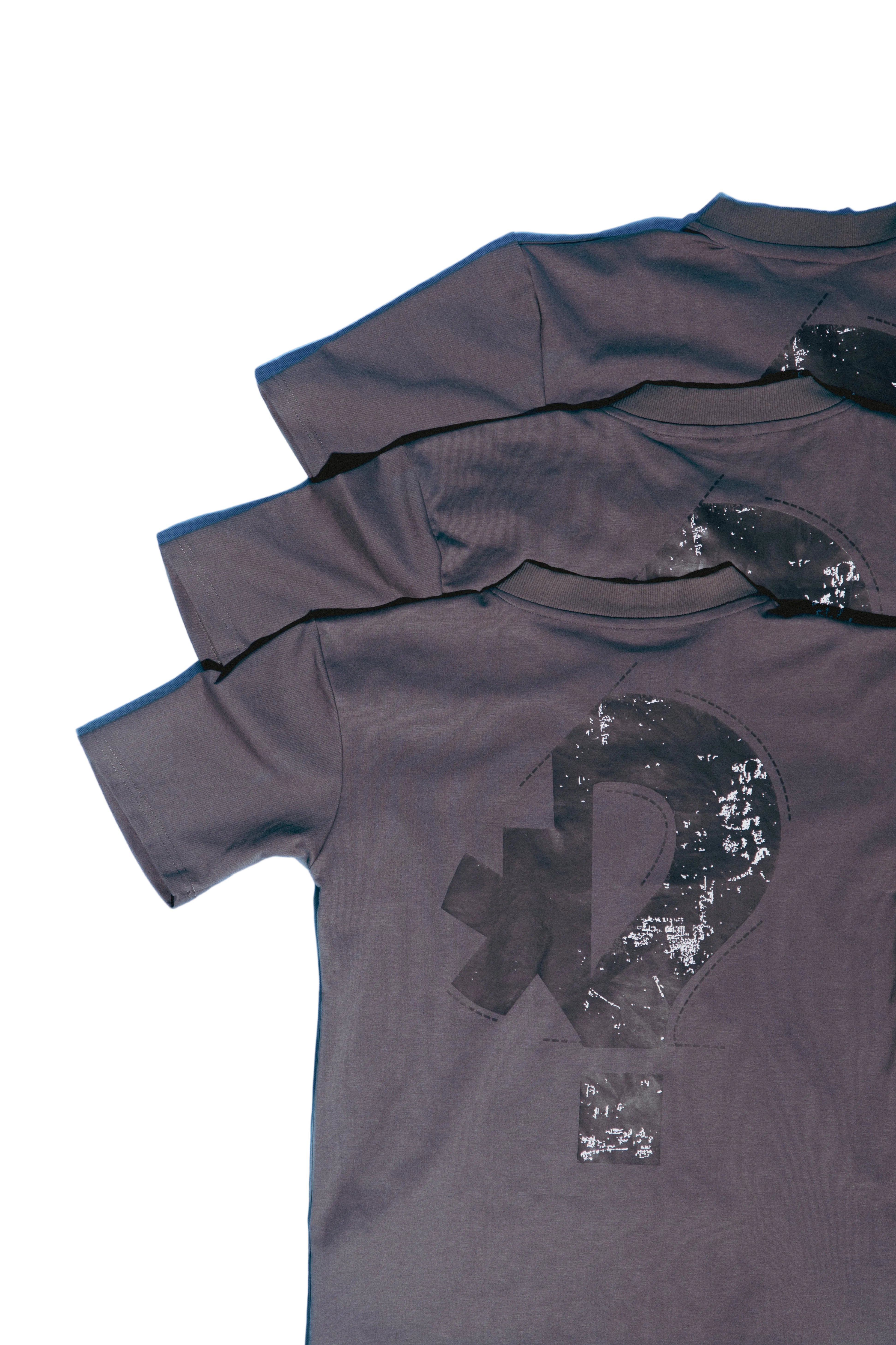Stack of dark gray SOH Question t-shirts with a question mark design on a light blue background