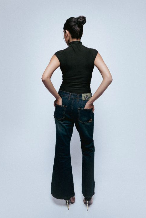 Person wearing a black sleeveless top and SOH Starlit Afterlight Indigo jeans on a light gray background